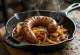 Boerewors z cebulą, papryką i przyprawami na patelni
